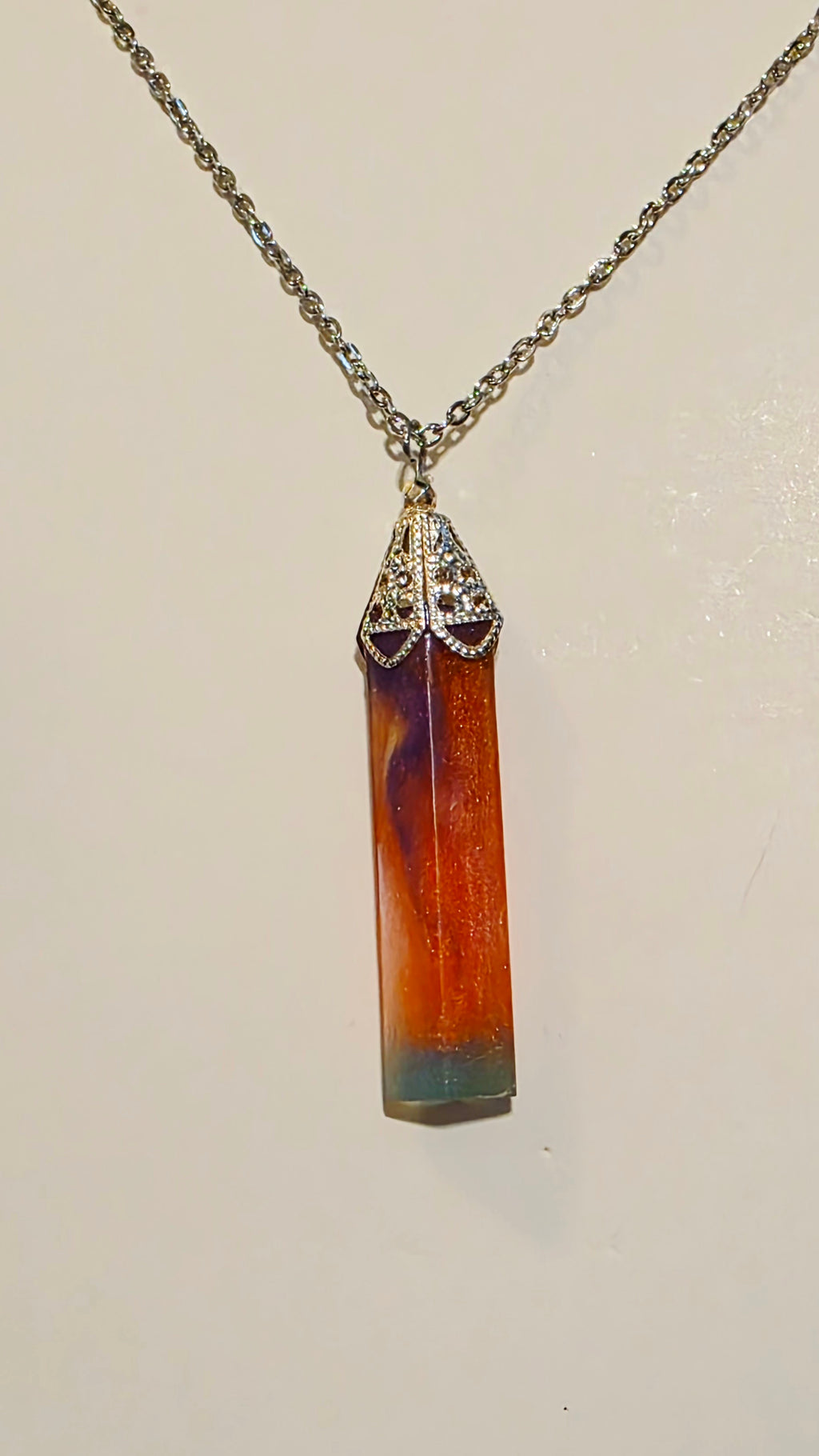Necklace with a cylindrical pendant on a plain background